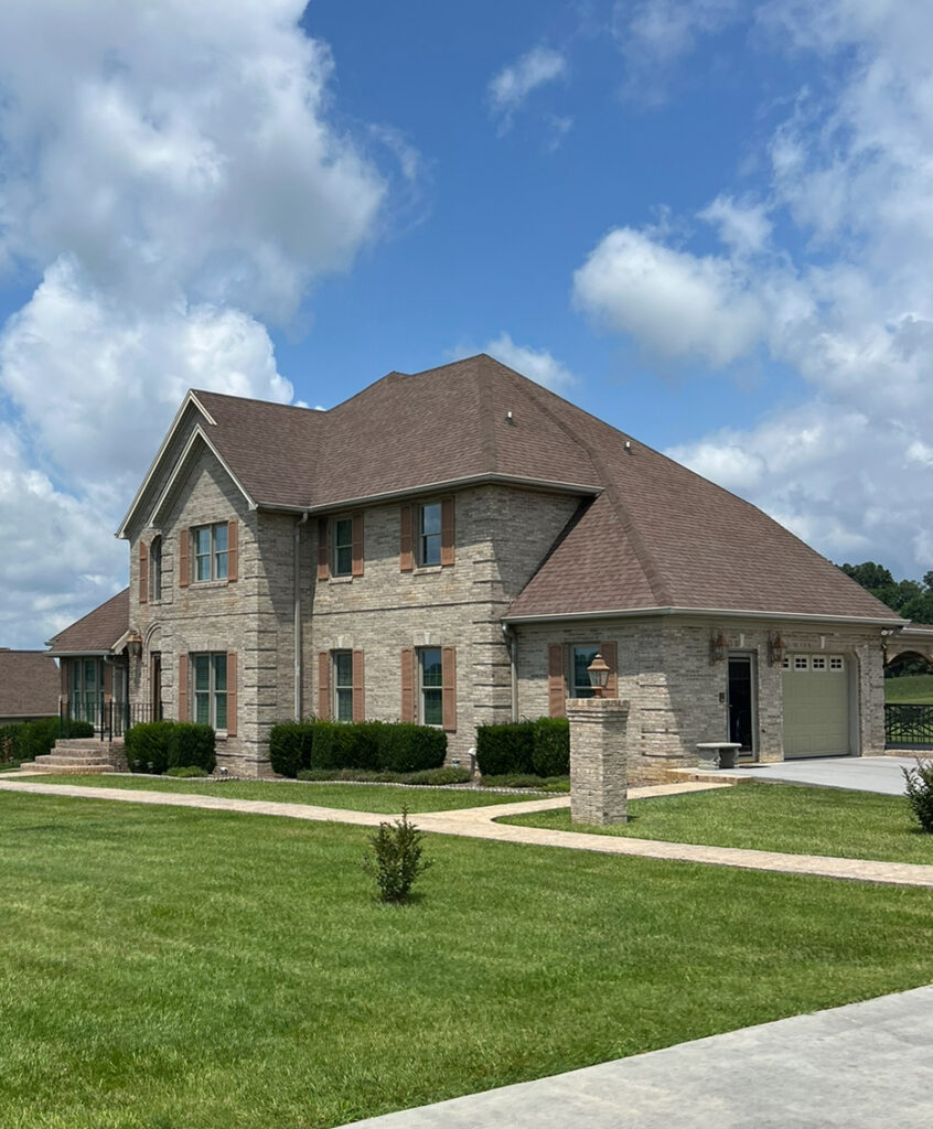 Brown shingle roof on a two-story stone home